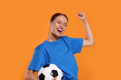 Photo of Happy fan with football ball on orange background