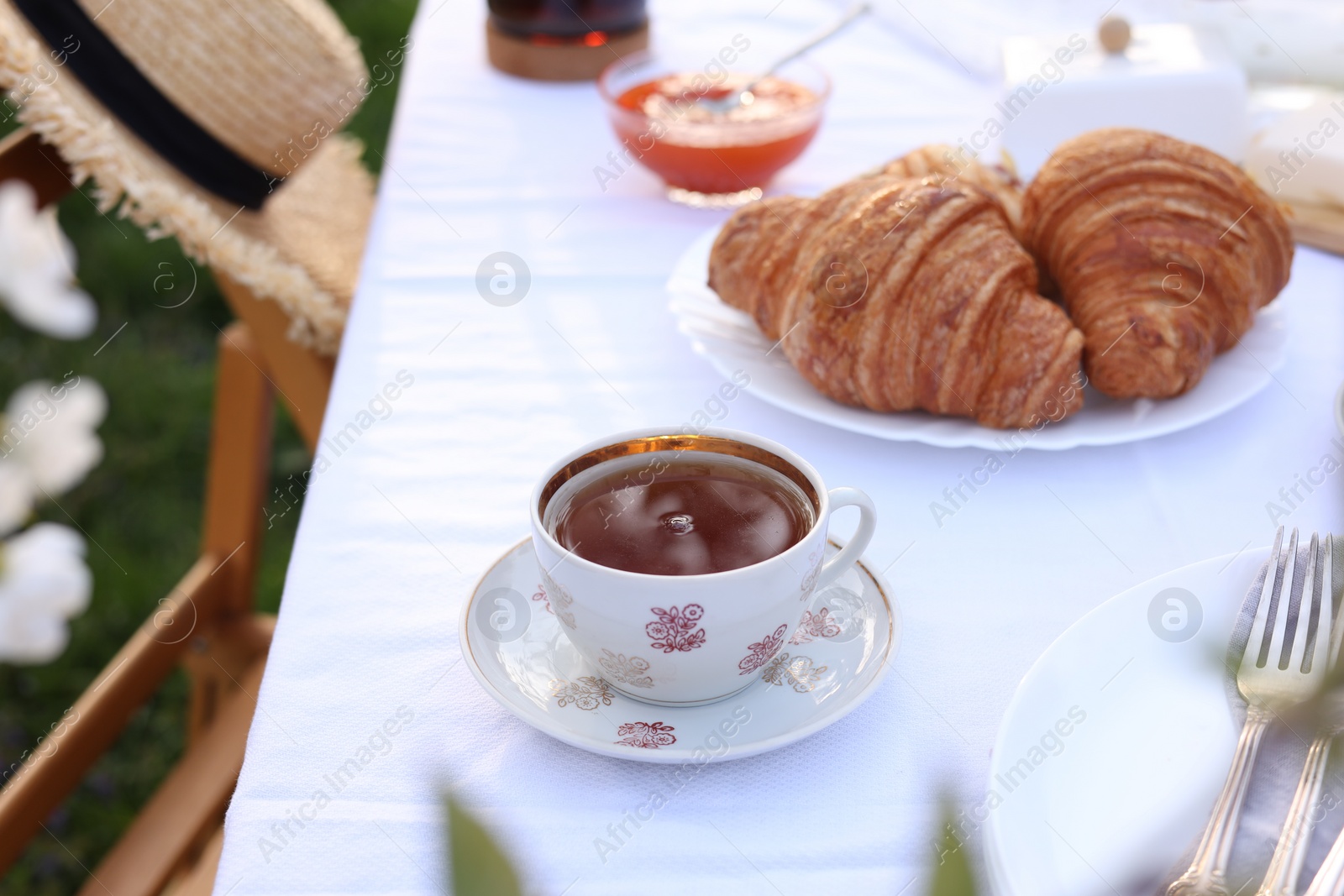 Photo of Stylish table setting with tea and croissants in spring garden