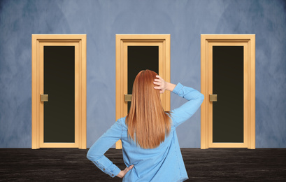 Image of Woman standing in front of similar doors. Choice concept
