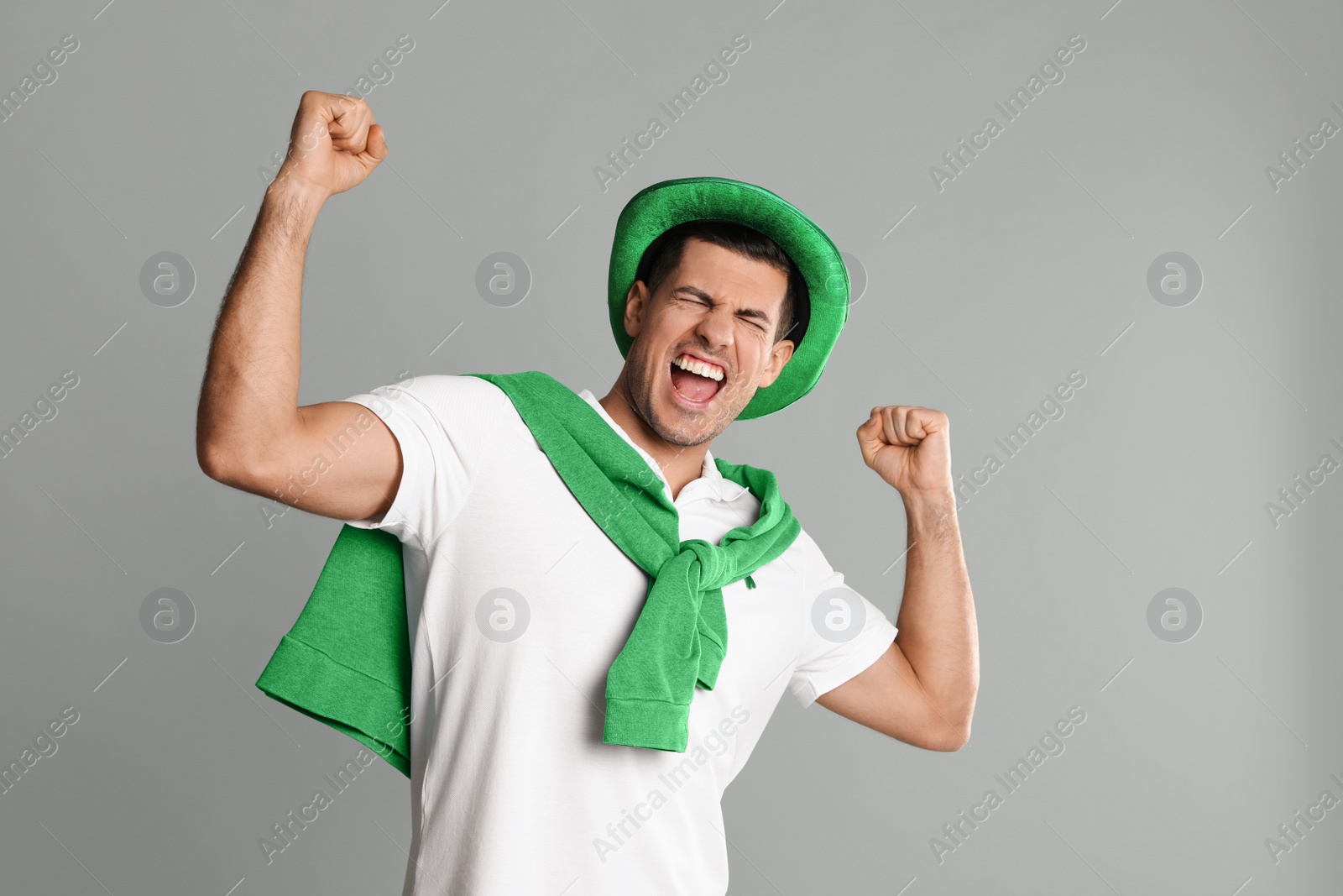 Photo of Emotional man in St Patrick's Day outfit on light grey background