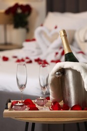 Honeymoon. Sparkling wine and glasses on wooden table in room