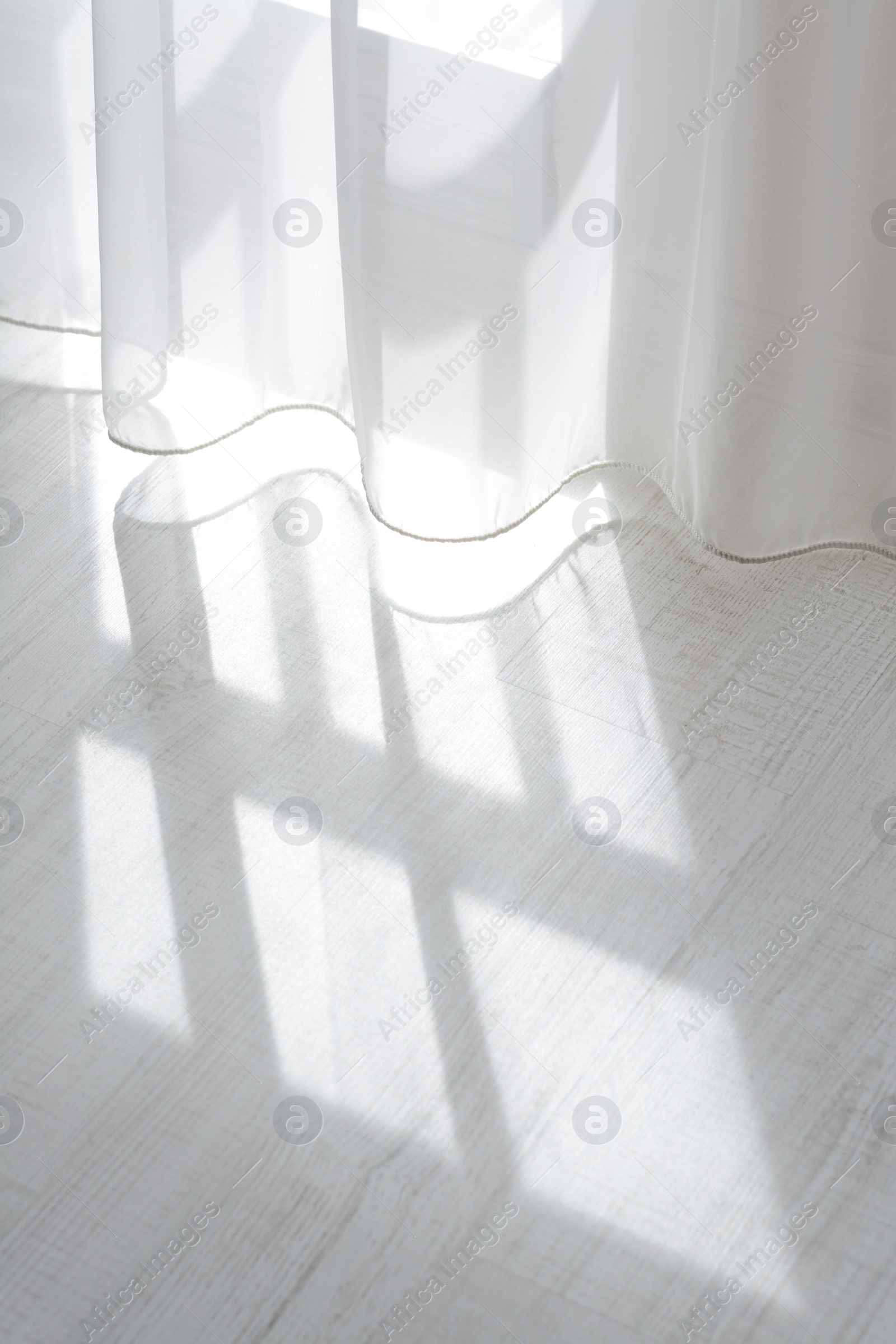 Photo of Curtain over sunlit wooden floor in morning