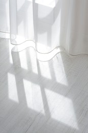 Curtain over sunlit wooden floor in morning