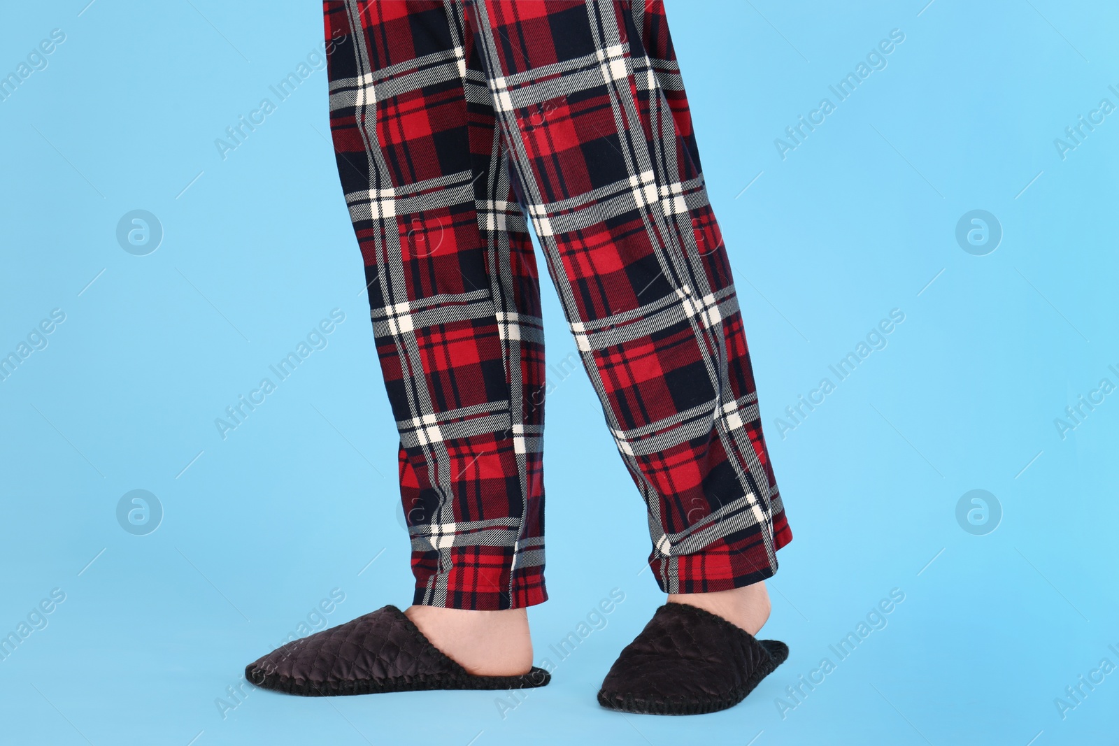 Photo of Man in warm soft slippers on light blue background, closeup