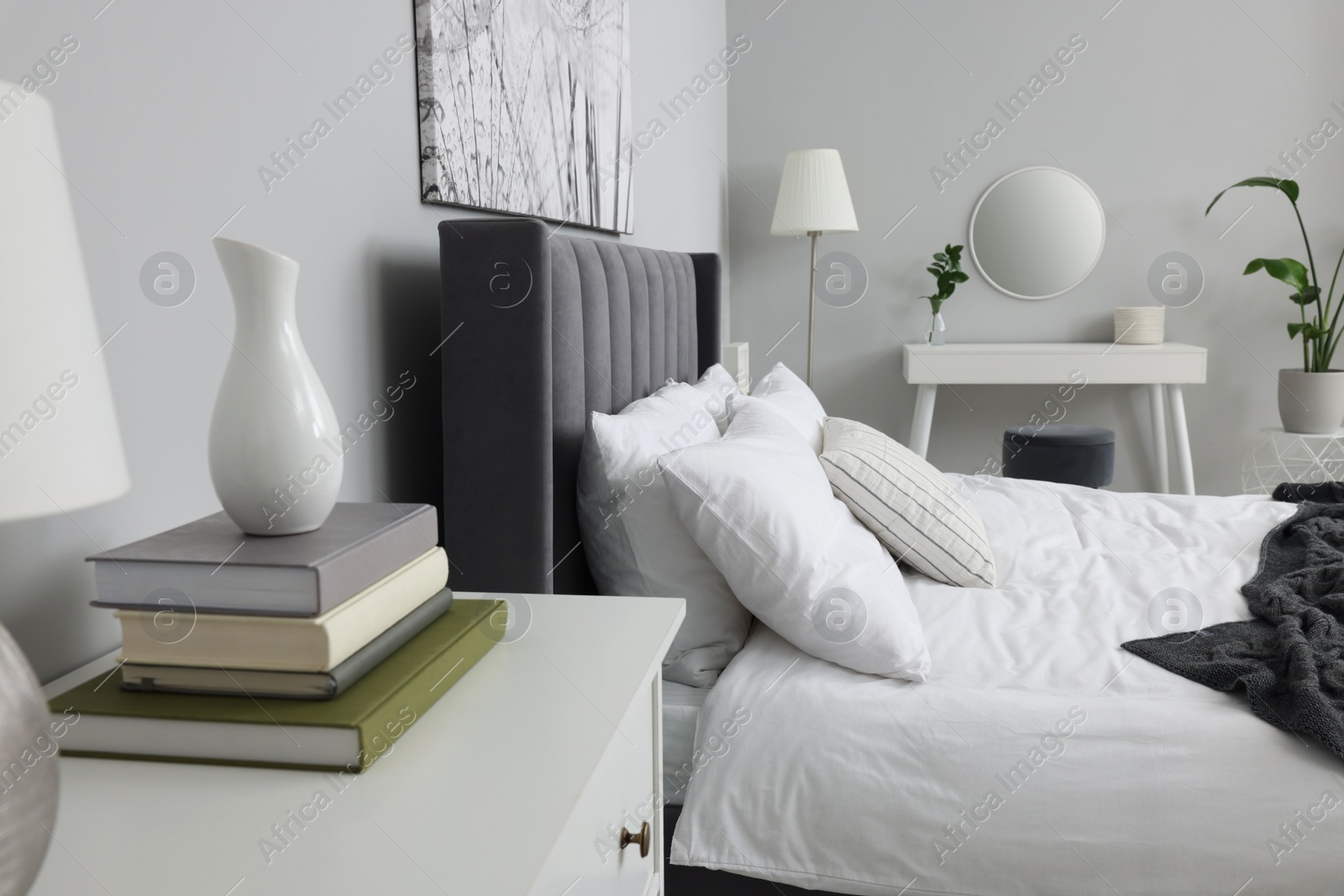 Photo of Stylish bedroom interior with large comfortable bed, chest of drawers and dressing table