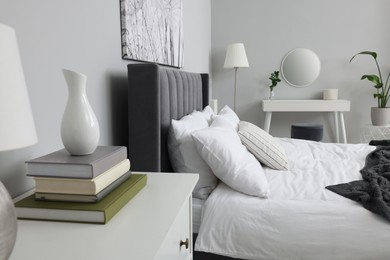 Photo of Stylish bedroom interior with large comfortable bed, chest of drawers and dressing table