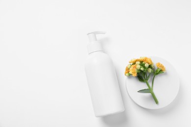 Photo of Bottle of cosmetic product, flowers and podium on white background, flat lay. Space for text