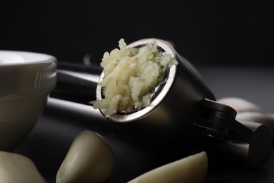 Garlic press, cloves and mince on grey table, closeup