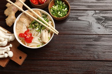 Photo of Delicious ramen with meat and ingredients on wooden table, flat lay. Space for text