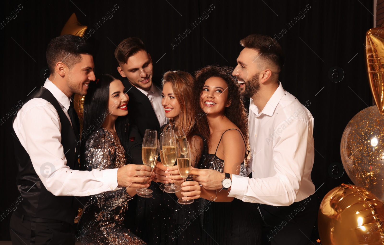 Photo of Happy friends with glasses of sparkling wine celebrating New Year on black background