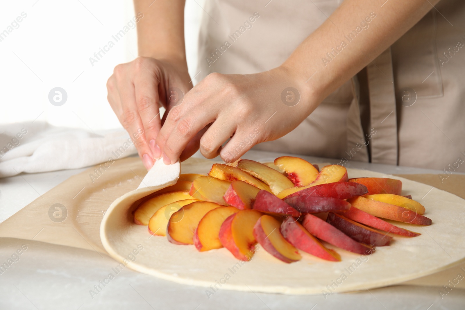 Photo of Woman making peach pie at kitchen table, closeup