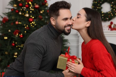 Photo of Beautiful young woman thanking her boyfriend for Christmas gift at home