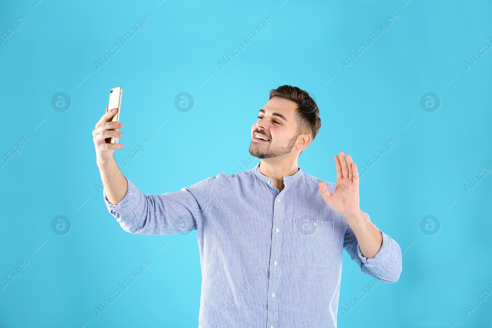 Photo of Man using mobile phone for video chat on color background