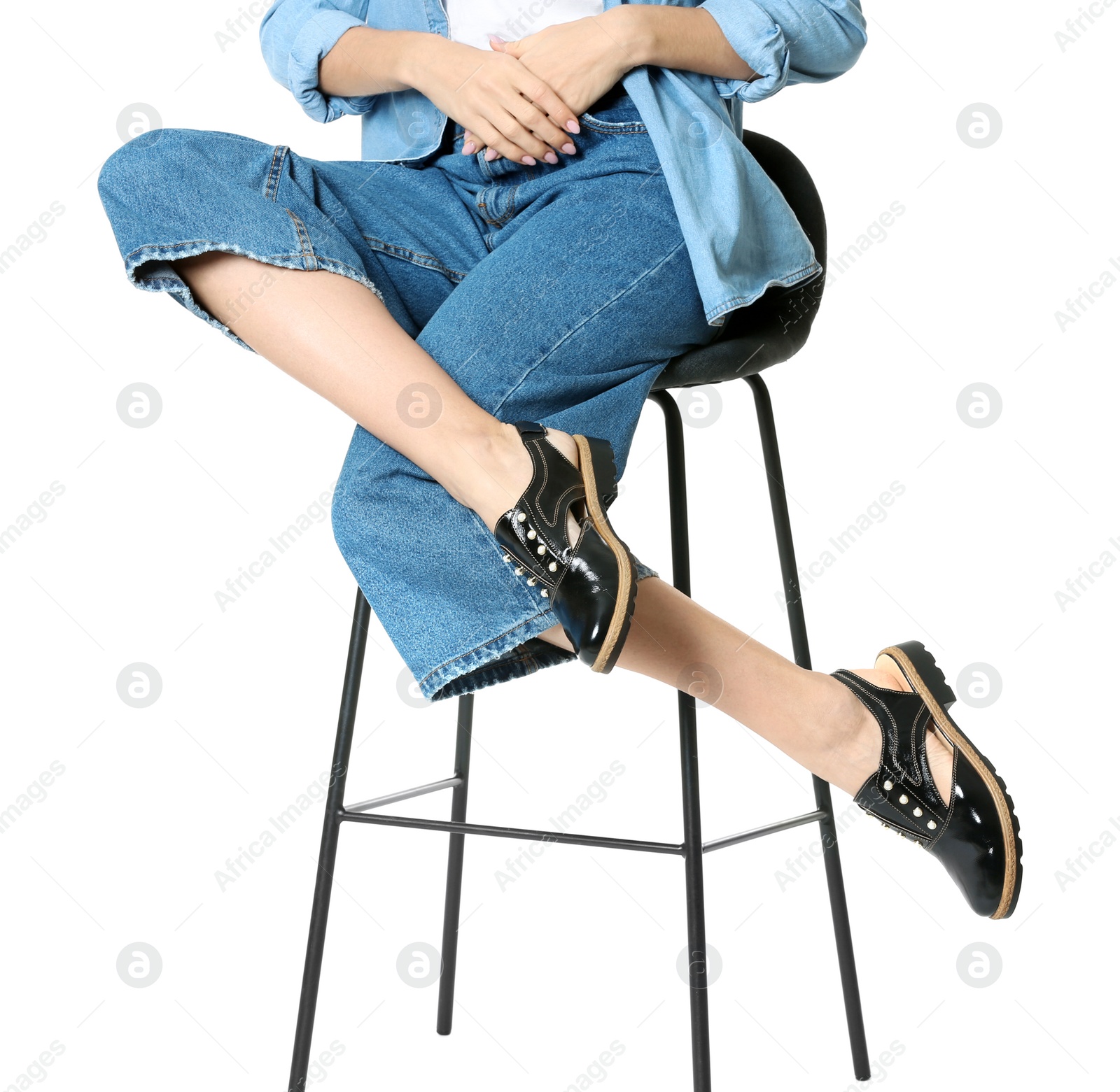 Photo of Woman in stylish shoes on stool against white background, closeup