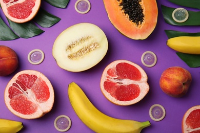 Photo of Flat lay composition with condoms and exotic fruits on purple background. Erotic concept