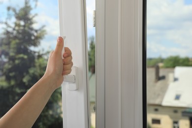 Photo of Woman opening white plastic window indoors, closeup. Space for text