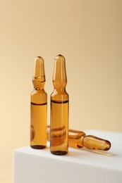 Photo of Glass ampoules with liquid on beige background