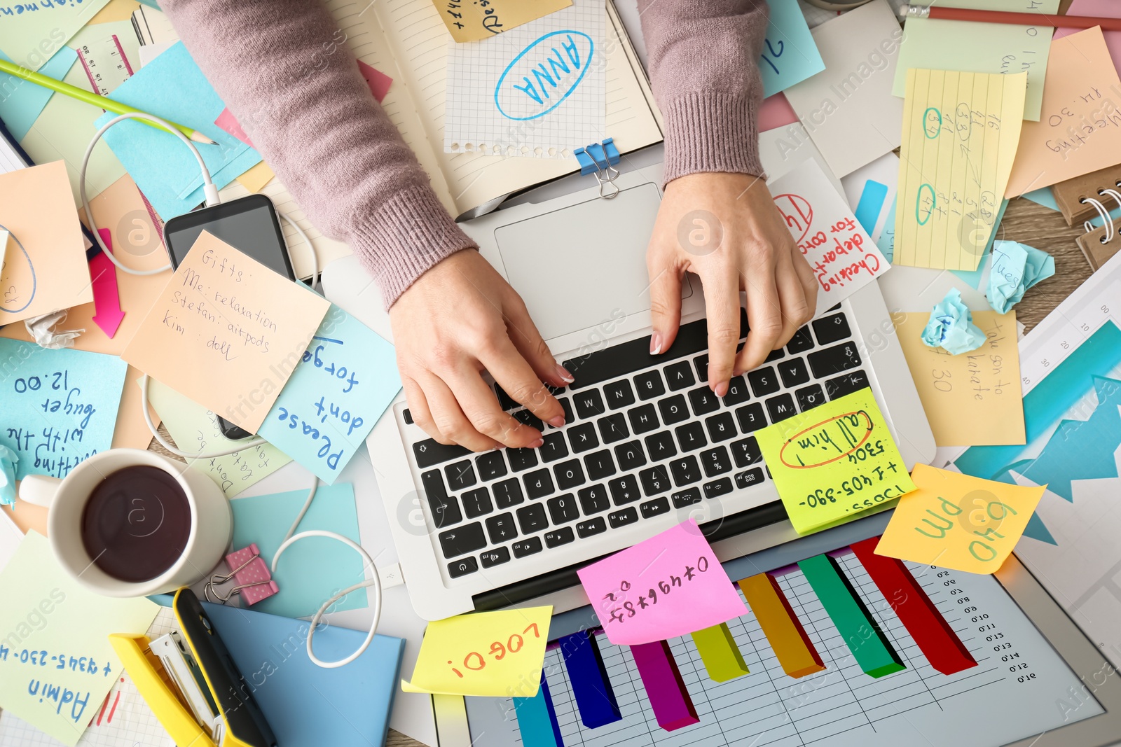 Photo of Overwhelmed woman working at messy office desk, top view