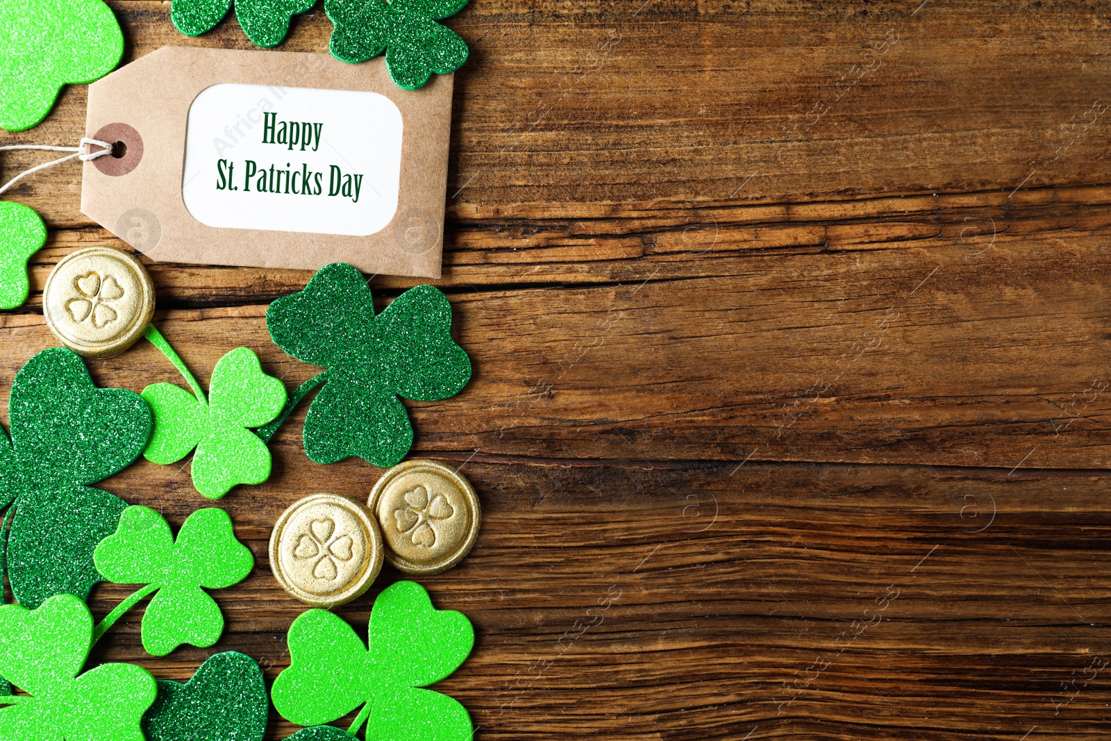 Photo of Flat lay composition with clover leaves and gold coins on wooden table, space for text. St. Patrick's Day celebration