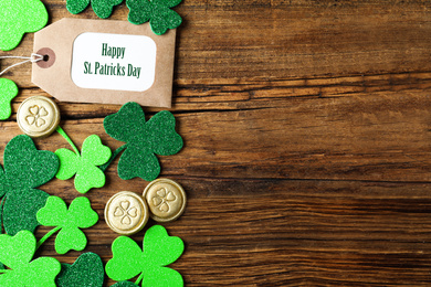 Flat lay composition with clover leaves and gold coins on wooden table, space for text. St. Patrick's Day celebration