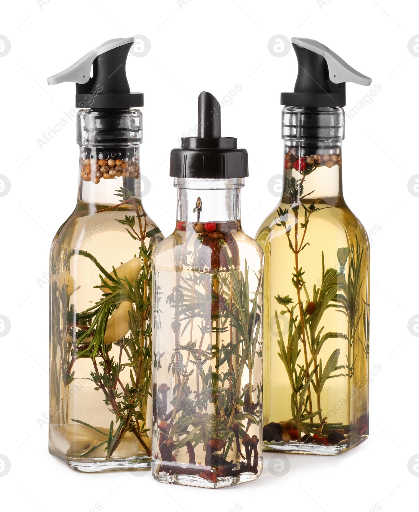 Photo of Different sorts of cooking oil with spices and herbs in bottles on white background