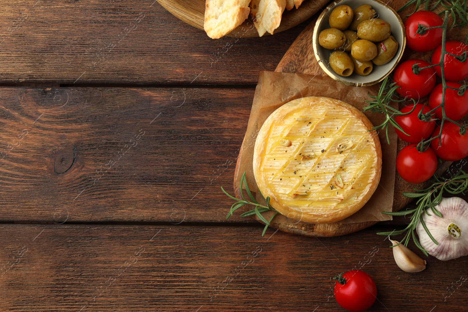 Photo of Tasty baked brie cheese served on wooden table, flat lay. Space for text
