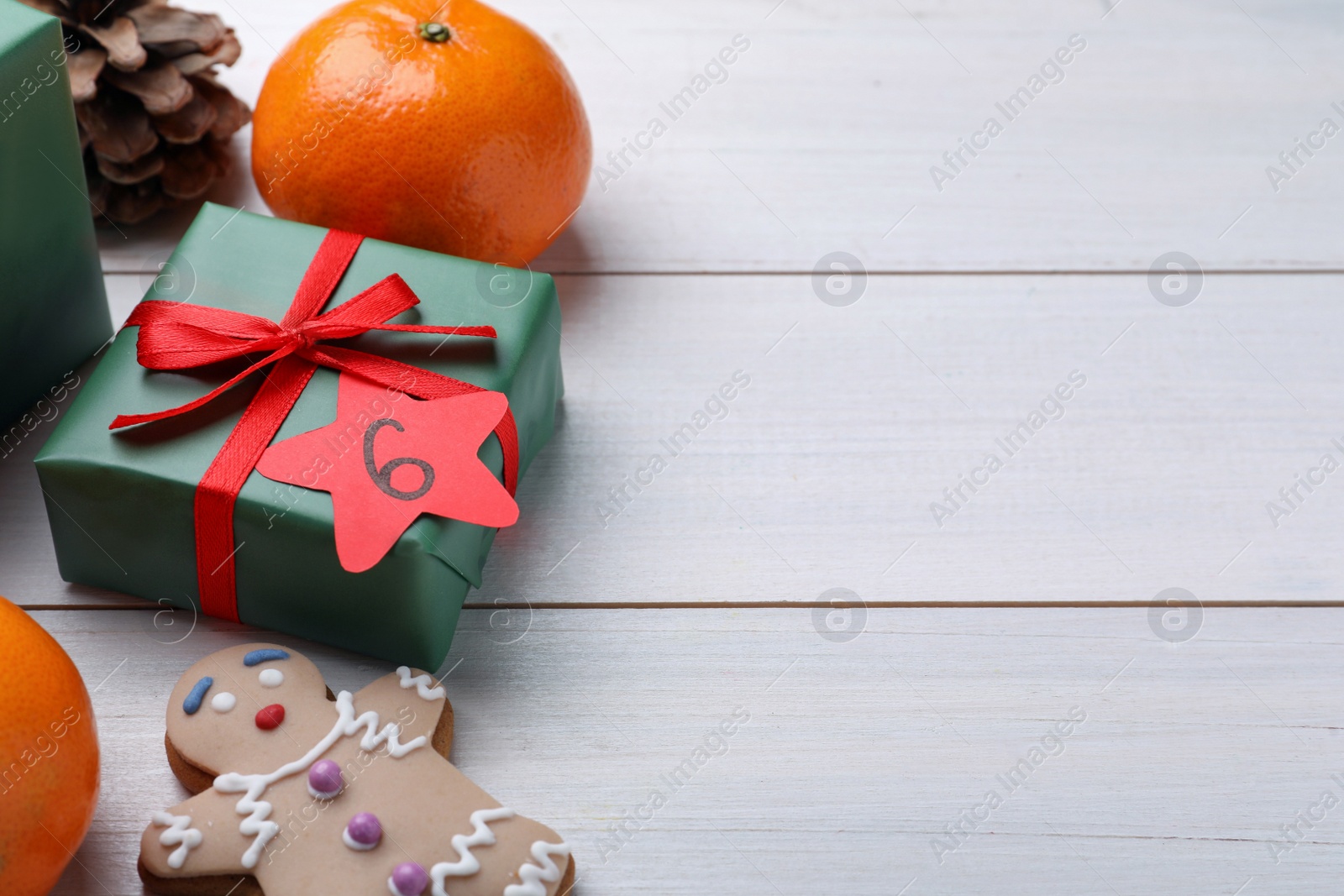 Photo of Gift boxes with paper tag and treats on white wooden table, space for text. December, 6 - Saint Nicholas Day