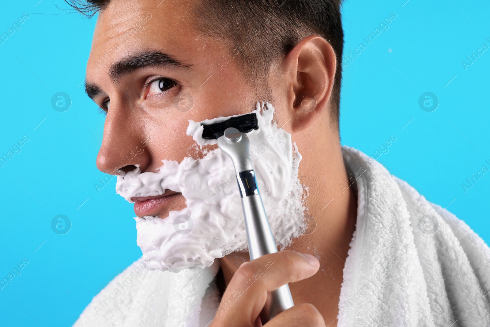 Photo of Handsome young man shaving on color background