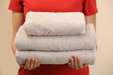 Photo of Woman holding fresh towels on color background, closeup