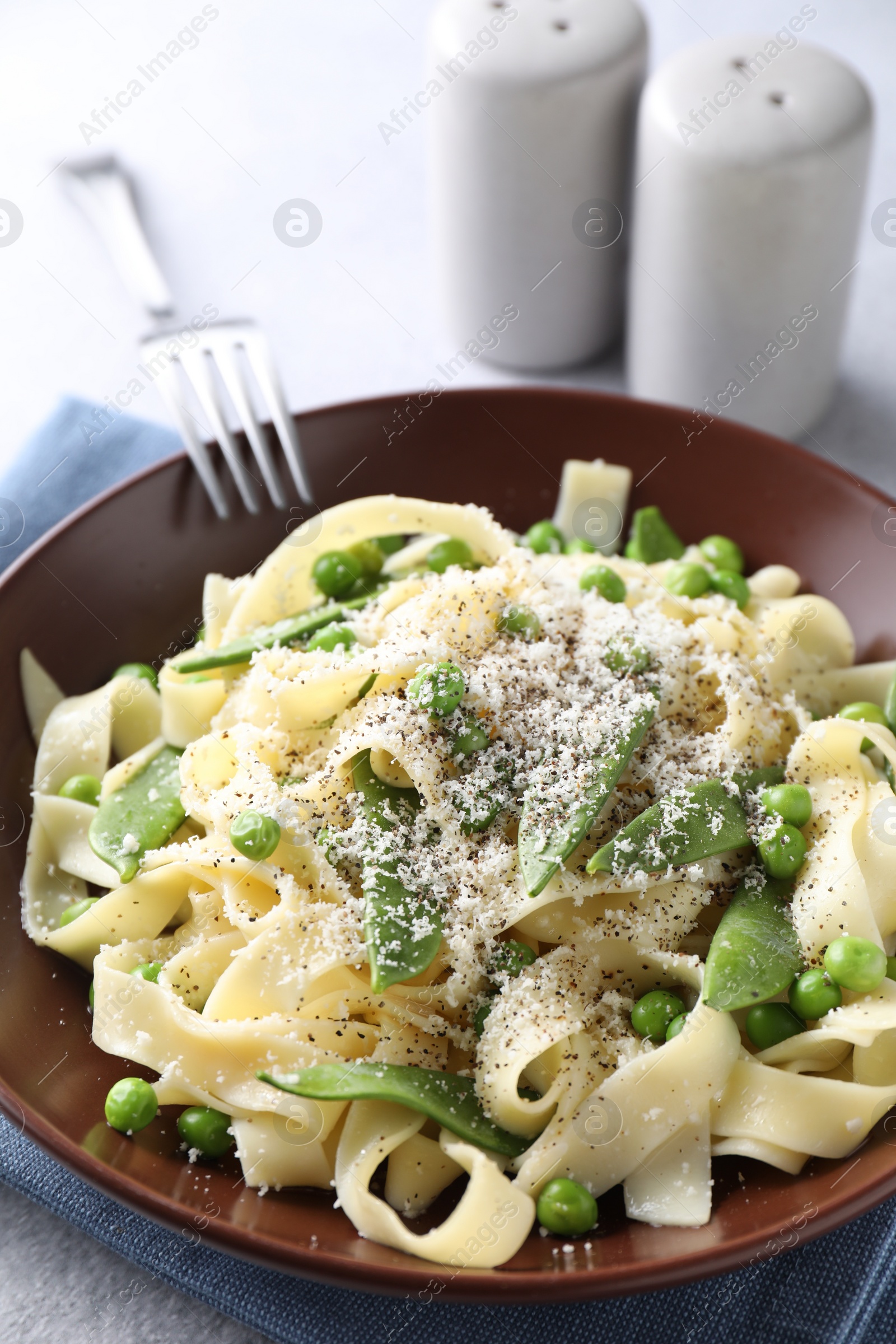 Photo of Delicious pasta with green peas and cheese served on grey table