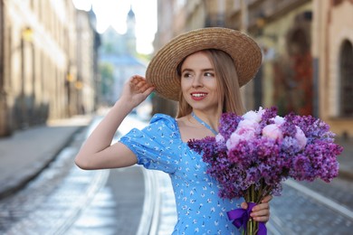 Beautiful woman with bouquet of spring flowers on city street