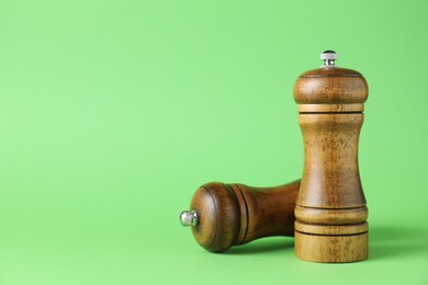 Photo of Wooden salt and pepper shakers on green background, closeup. Space for text
