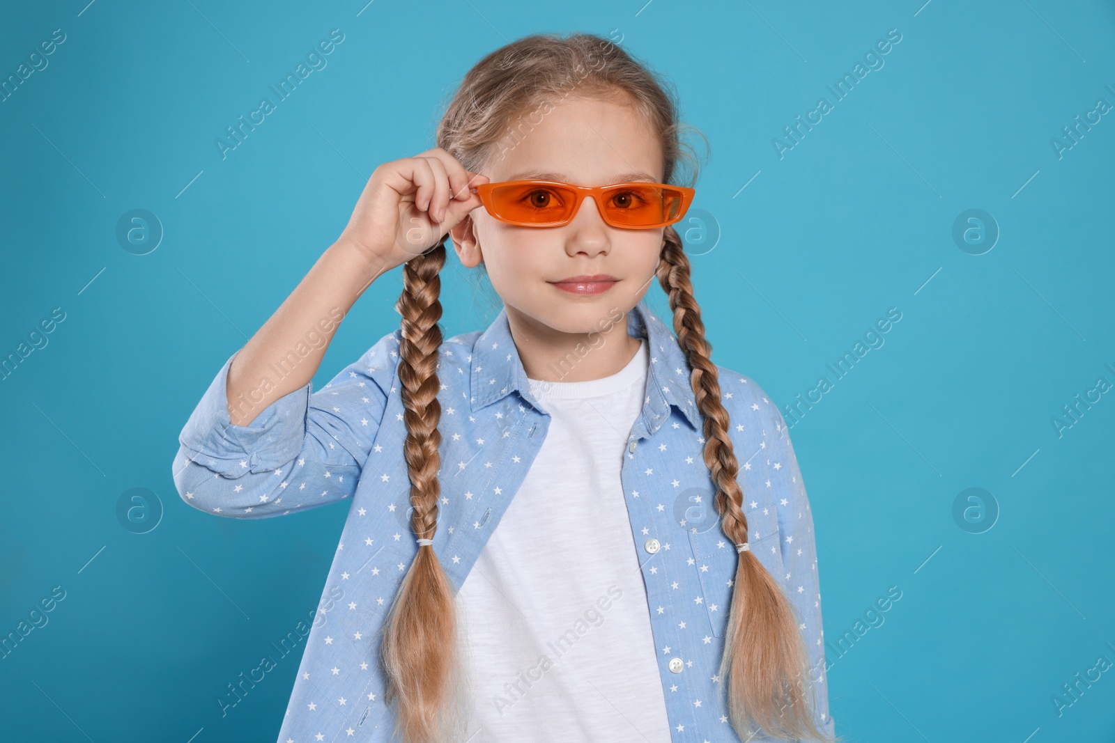 Photo of Girl in orange sunglasses on light blue background