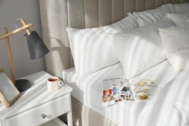 Magazine on bed with clean white linens indoors