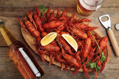 Flat lay composition with delicious red boiled crayfishes on wooden table