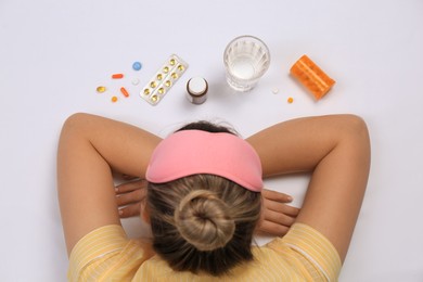 Photo of Woman surrounded by different pills on white background, top view. Insomnia treatment