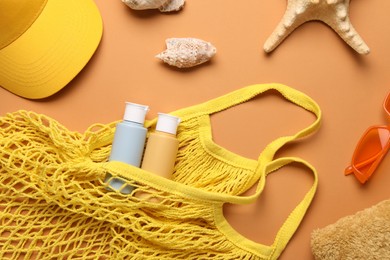 String bag and different beach accessories on pale orange background, flat lay