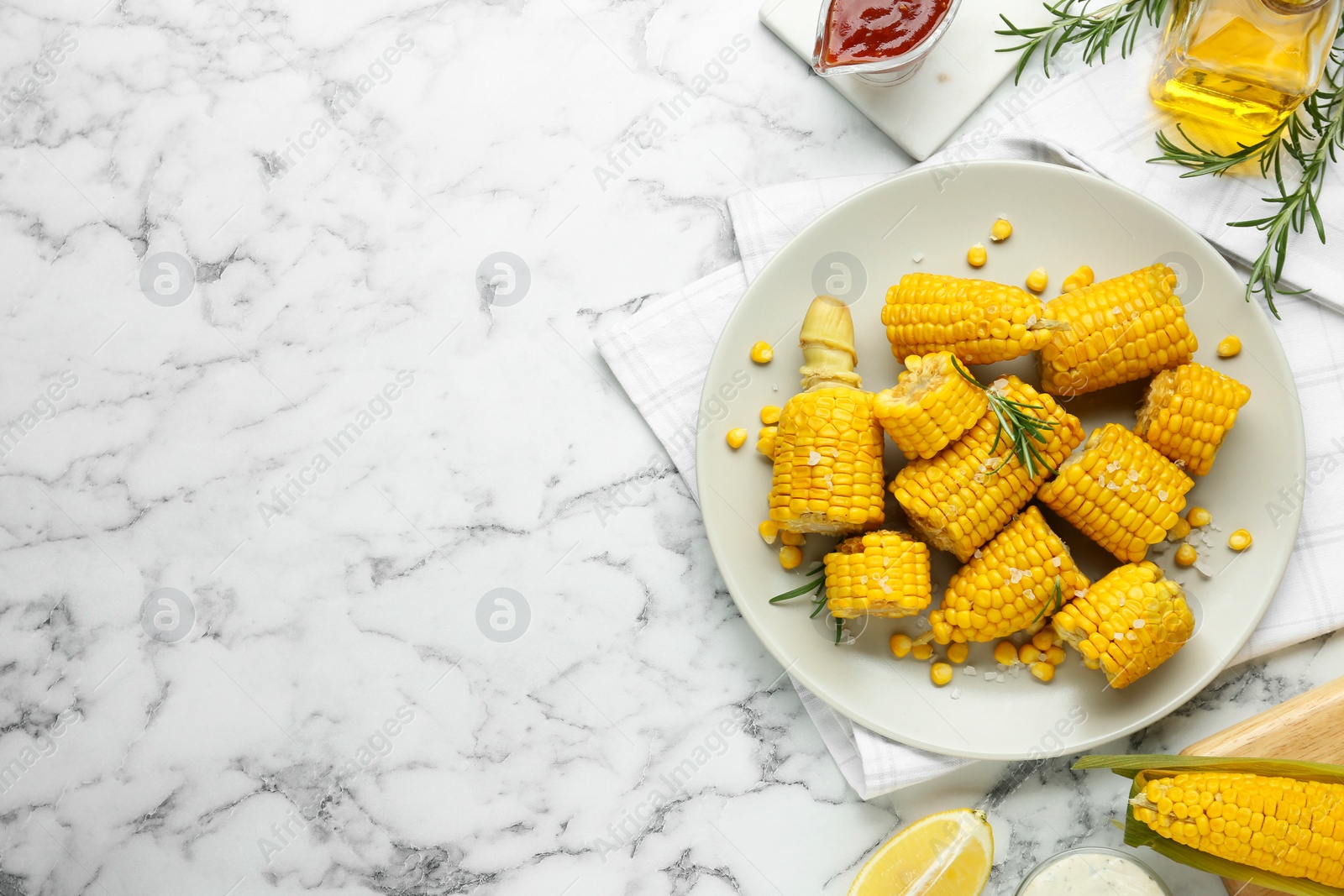 Photo of Plate with tasty cooked corn cobs on white marble table, flat lay. Space for text