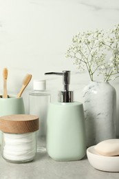 Photo of Different bath accessories, personal care products and gypsophila flowers in vase on gray table near white wall