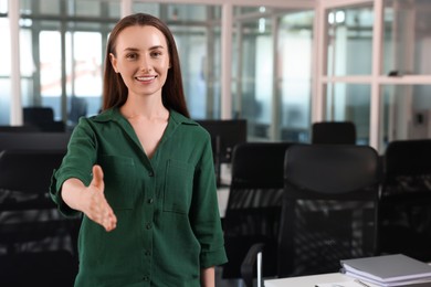 Happy woman welcoming and offering handshake in office, space for text