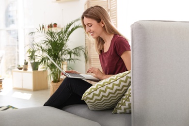 Photo of Young woman using laptop at home. Trendy room interior with plants