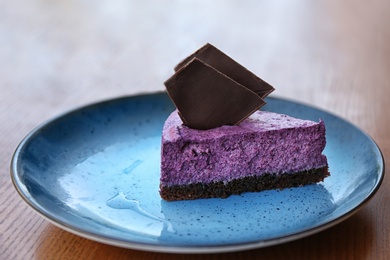 Plate with slice of berry cheesecake on wooden table