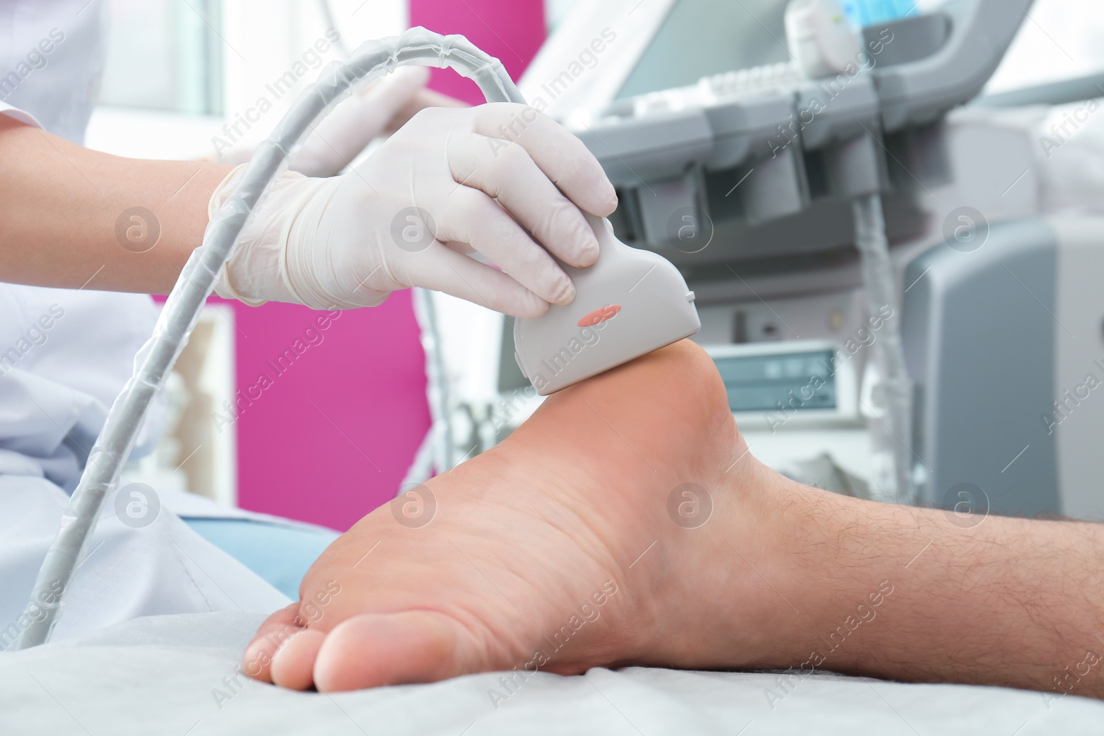 Photo of Doctor conducting ultrasound examination of patient's foot in clinic, closeup