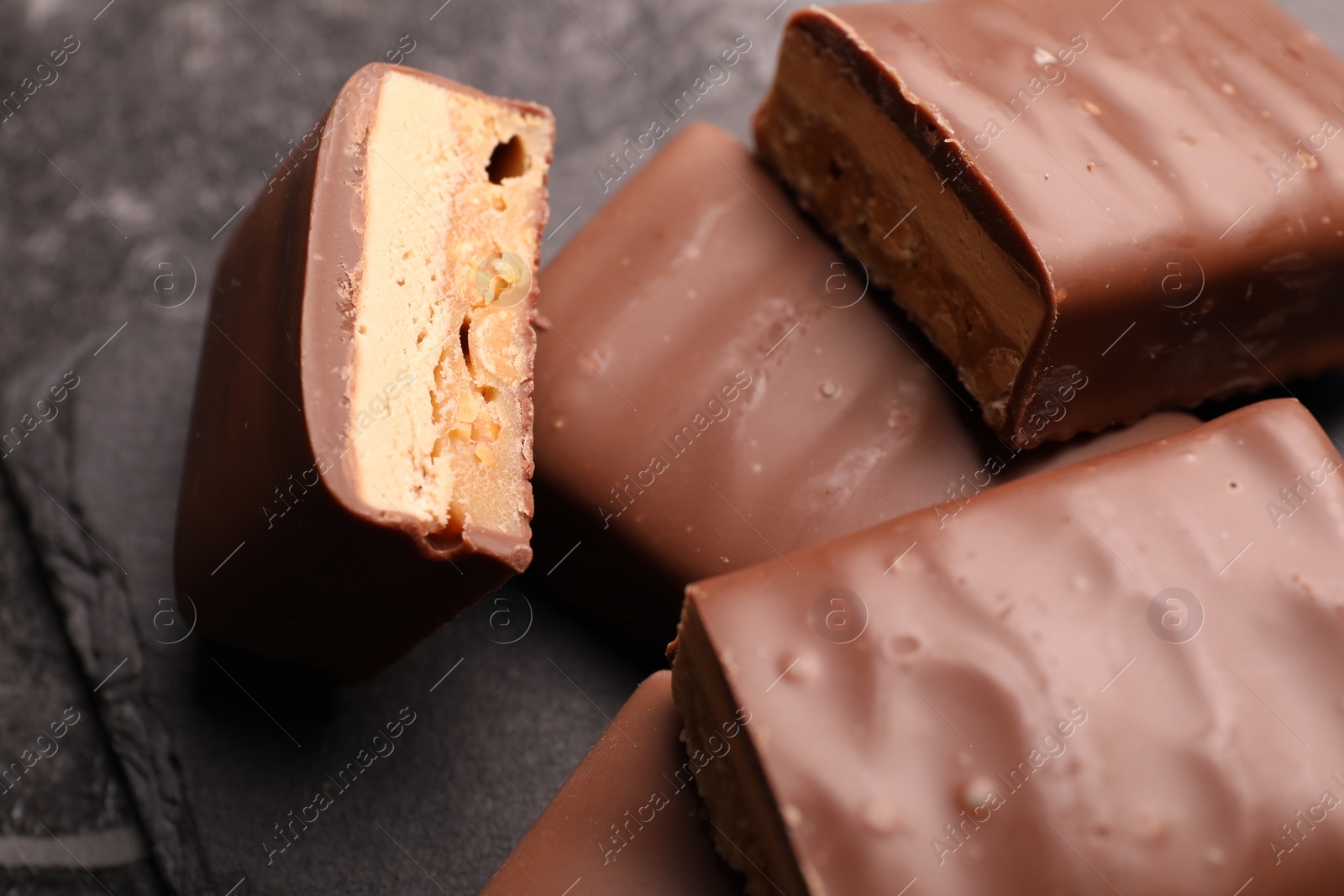 Photo of Tasty chocolate bars with nougat on gray table, closeup