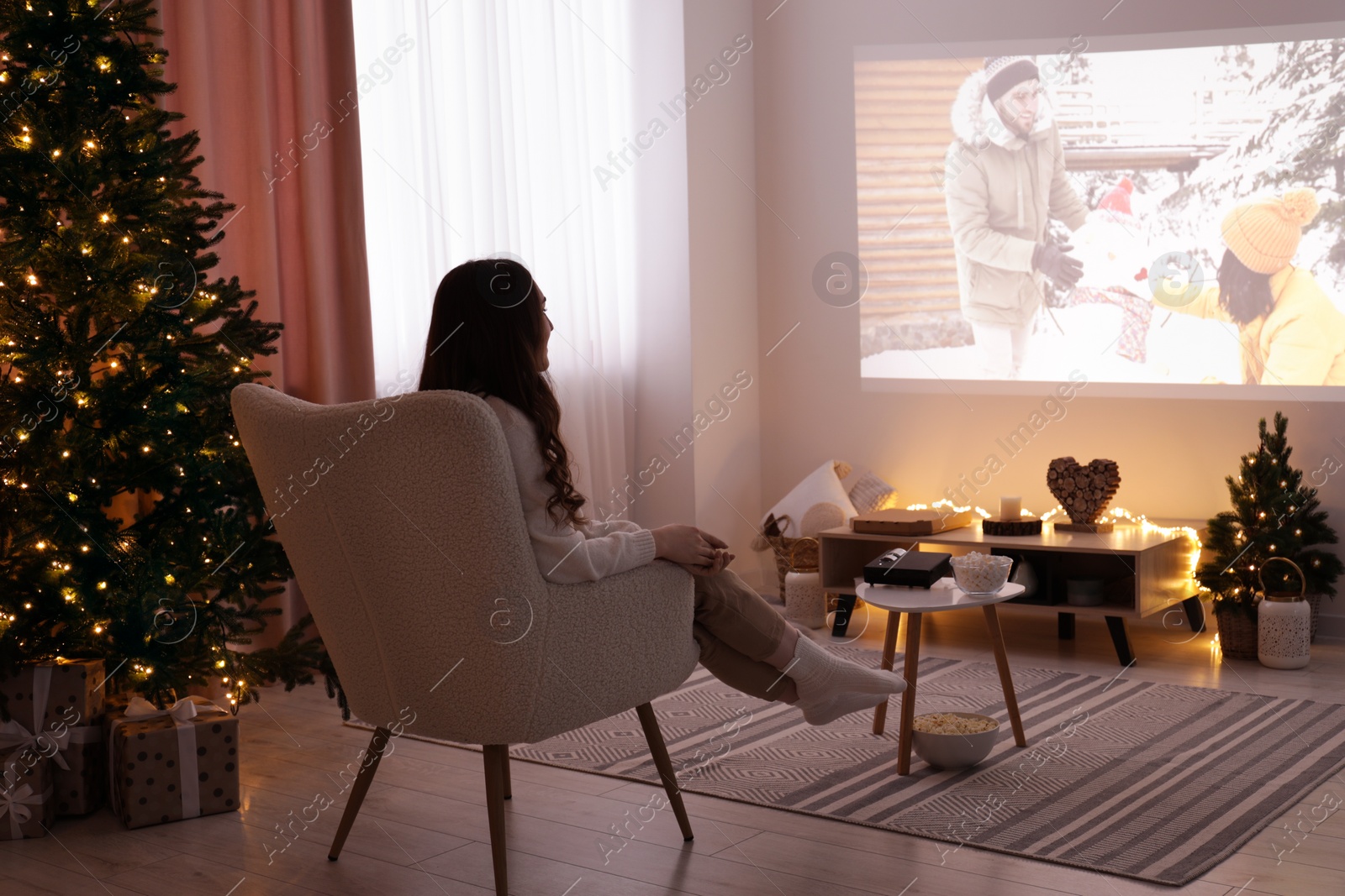 Photo of Woman watching romantic Christmas movie via video projector at home