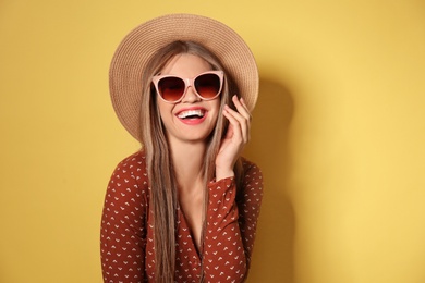 Photo of Young woman wearing stylish sunglasses and hat on yellow background