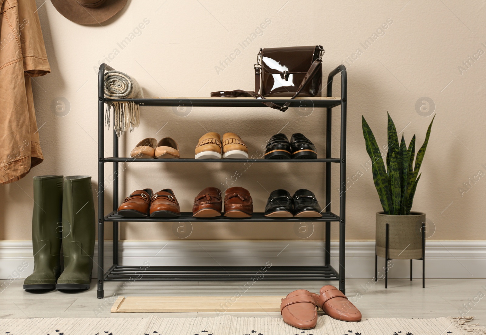 Photo of Rack with different shoes near beige wall in room