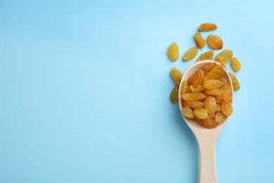 Photo of Spoon of raisins on color background, top view with space for text. Dried fruit as healthy snack
