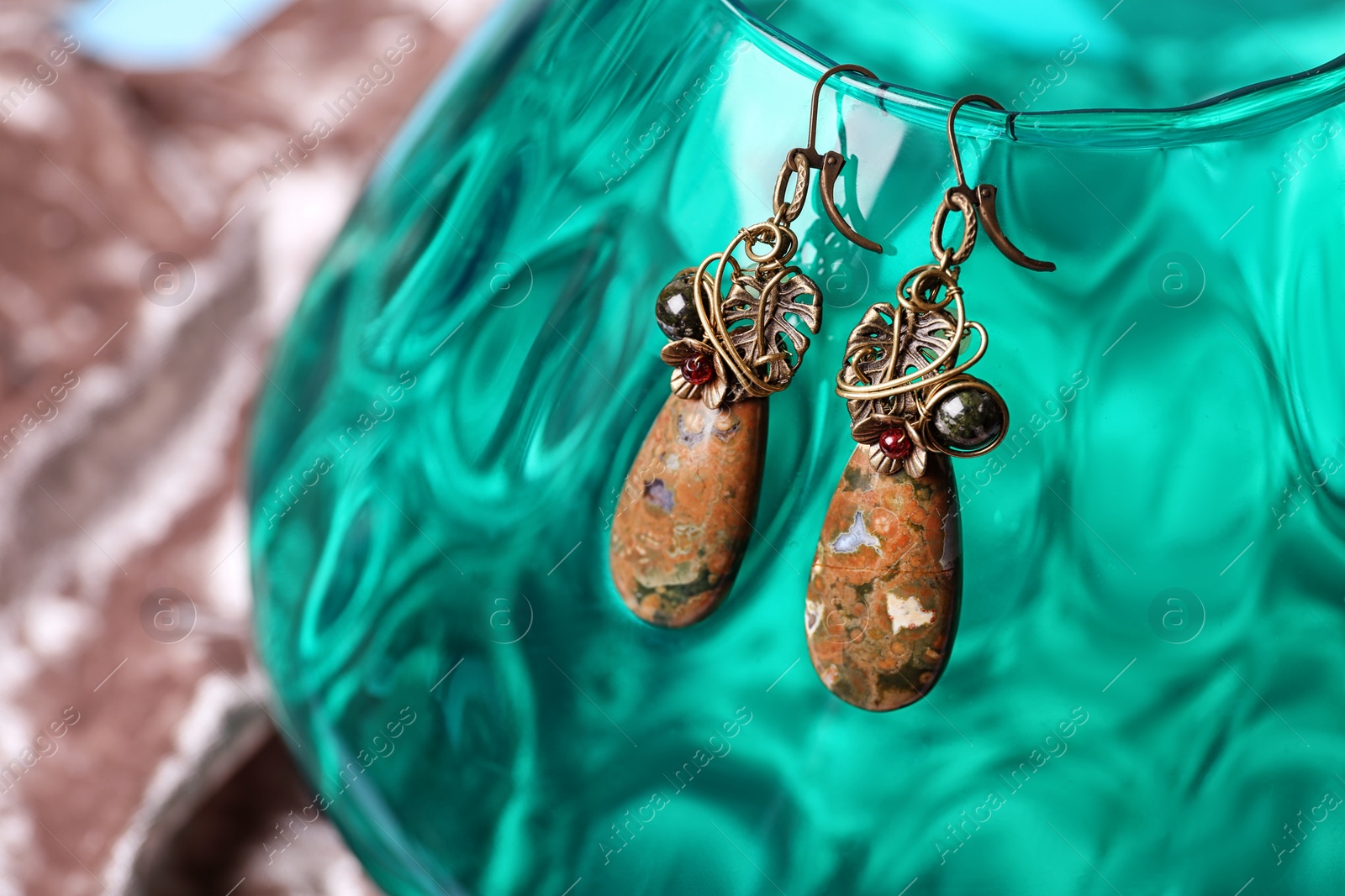 Photo of Beautiful pair of metal earrings with jasper gemstones on glass stand