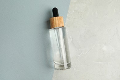 Photo of Bottle of face serum on color background, top view
